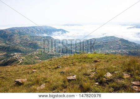 Clouds mist moves through rural valley hills covering homes over scenic landscape.