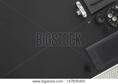 Work space on black table of a creative designer or photographer with laptop tablet camera and other objects of inspiration and copy space. Stylish home studio concept of technology trends.