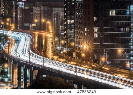 Glowing light streaks from a wet Gardiner Expressway as traffic never stops.  Hot & rainy, muggy summer night in Lakeside Toronto Ontario, Canada.