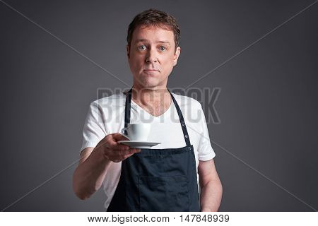 A middle age man serve a cup of coffee