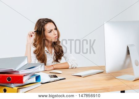 Concentrated pensive businesswoman thinking about something and scratching her head with pen isoltaed on the white background