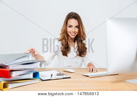 Smiling cheerful businesswoman sitting at her working place isoltaed on the white background