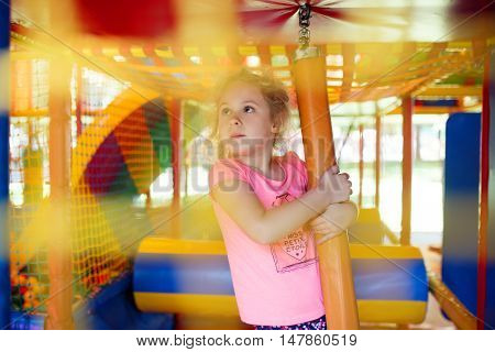 Cute little girl have fun at soft outdoor playground.