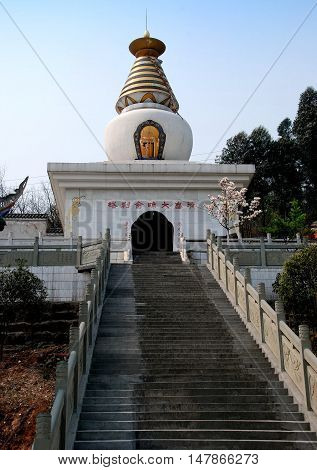 Dan Jing Shan China - March 16 2009: A long flight of stairs leads to a bulbous Tibetan style white dagoba at the Fo Shan Gu Si Buddhist Temple