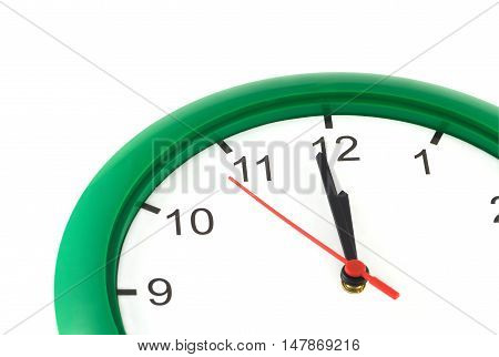 Fragment of big wall clock with green case shows almost twelve o'clock isolated on white closeup