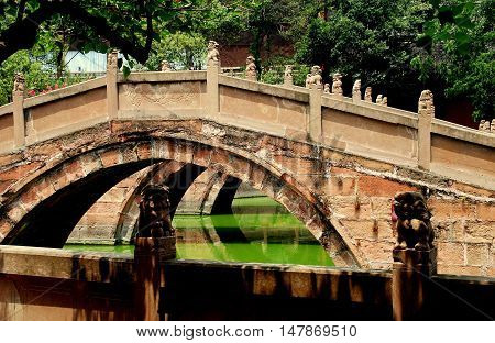 Deyang China - July 6 2007: Pink sandstone Pan Bridges span a lagoon at the 13th century Deyang Confucian Temple