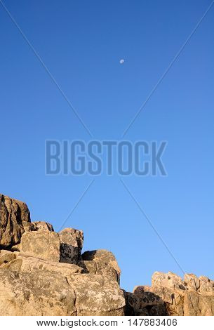 A waning moon over a rock outcropping on the summit of Mount Tai or Taishan located in Shandong province China.