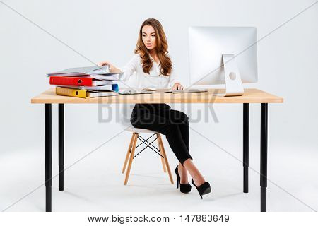 Attractive young businesswoman working with documents while sitting at the table isoltaed on the white background