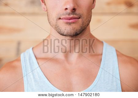 Closeup of serious confident young man over wooden background