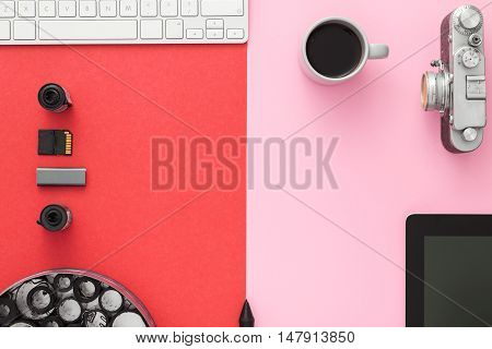 Work space on red table of a creative designer or photographer with laptop tablet camera and other objects of inspiration and copy space. Stylish home studio concept of technology trends. View from above.