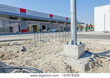 Fasteners - screws and nuts on quadratic concrete base of the electric metal lamppost.