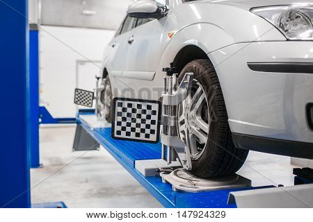 Car on stand with sensors on wheels for wheels alignment camber check in workshop of Service station.