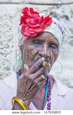 HAVANA CUBA - JULY 18 : A portrait of a Cuban woman smoking cigar in old Havana street on July 18 2016. Cuba now exports more than 90 million cigars a year