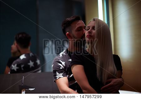 Sexy man kissing woman neck at mirror in bathroom passionate couple