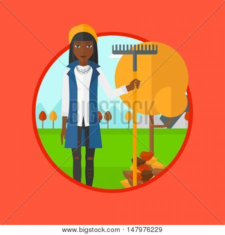An african woman raking autumn leaves. Woman with rake standing near tree and heap of leaves. Woman tidying leaves in garden. Vector flat design illustration in the circle isolated on background.