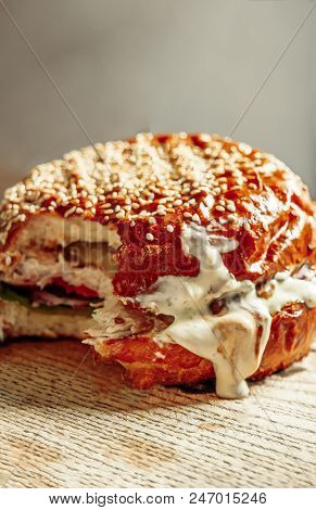 Bitten Hamburger On Wooden Board Closeup Image With Copyspace. A Fast Food Cheeseburger With A Bite 