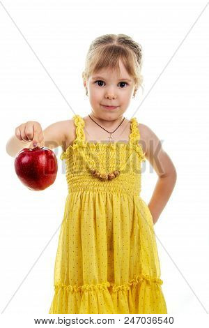 Little Girl In A Bright Yellow Dress With An Apple In Her Hands. Studio Photo, Bright Isolated Backg