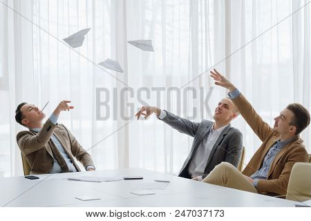 Business Men Throwing Paper Planes At The Board Meeting. Small Break From Work To Relax. Fun Workday