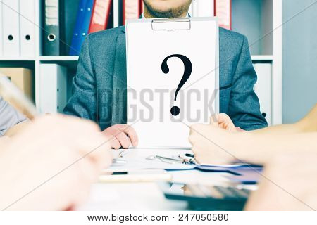Frustrated Business Man Showing Paper Sheet With Question Mark To His Colleagues On Business Meting.