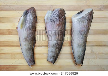 Three Pieces Of Fish Notothenia On A Cutting Board Close-up