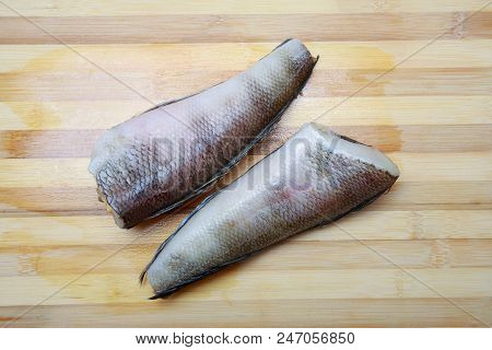 Two Pieces Of Fish Notothenia On A Cutting Board Close-up