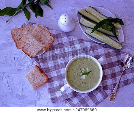Summer Cold Yoghurt Soup With Fresh Cucumber, Green Peas And Mint On A Gray Concrete Background