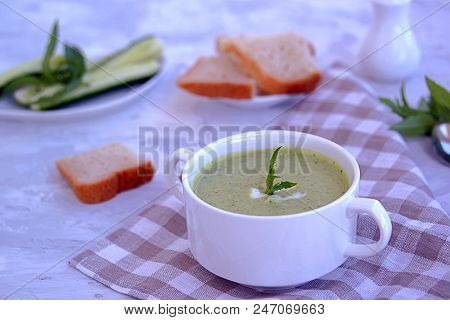 Summer Cold Yoghurt Soup With Fresh Cucumber, Green Peas And Mint On A Gray Concrete Background