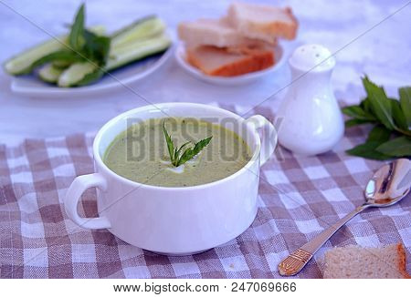 Summer Cold Yoghurt Soup With Fresh Cucumber, Green Peas And Mint On A Gray Concrete Background