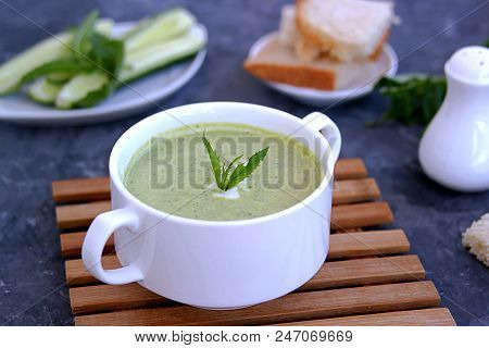 Summer Cold Yoghurt Soup With Fresh Cucumber, Green Peas And Mint On A Gray Concrete Background