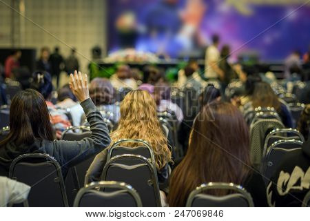 Speaker On The Stage With Rear View Of Audience In Put Hand Up Acton For Question In The Meeting Or 