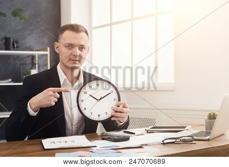 Serious Businessman Holding Clock And Pointing At It. Time Is Money, Dont Waste It, Copy Space