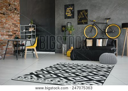 Real Photo Of A Teenager's Bedroom Interior With Black Bed, Bike On The Bedhead, Yellow Chair At Des