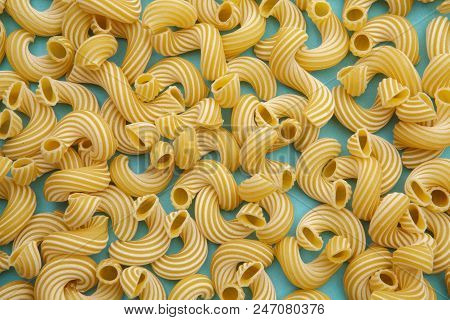 Ellow Background Of Pasta In The Form Of Tubes Spun In A Spiral