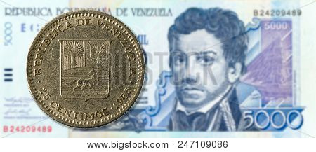 25 Centimos Coin Against 5000 Venezuelan Bolivar Bank Note (blue) Obverse