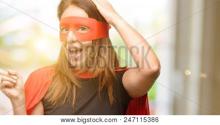 Middle age super hero woman wearing red mask and cape pointing away side with finger
