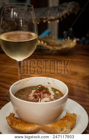 Gumbo And Wine On The Table With A Gator In The Background