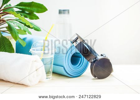 Set For Sports. Blue Yoga Mat Towel Headphones And A Bottle Of Water On A Light Background The Conce