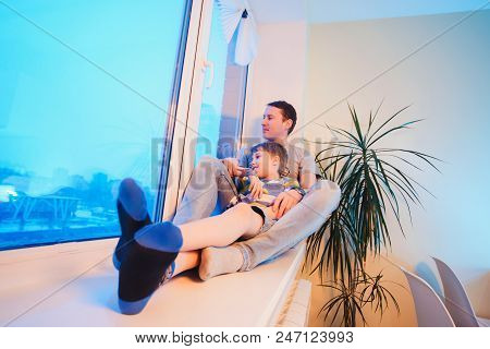 Parents And Kids Sitting Near Window And Having Fun At Kitchen. Father And Son On The Windowsill Clo