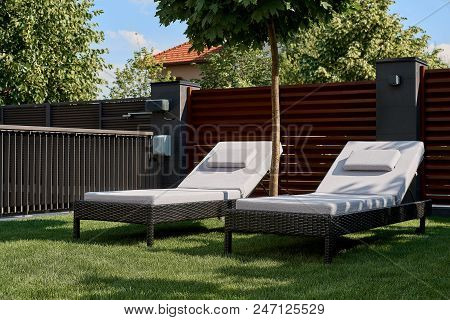 Two Chaise Lounges Are On The Green Lawn In The Courtyard Of The House. Concept Of Relaxation, Rest,