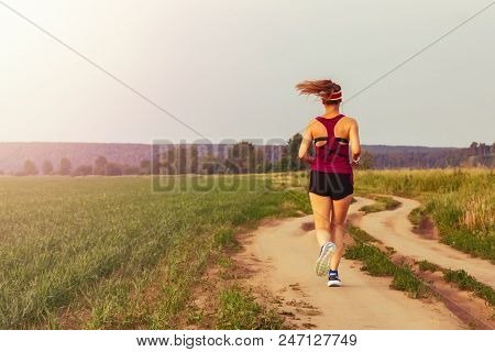 Sport Teenage Girl Running Outdoor. Young Woman Running In Field At Evening. Back View Of Running La