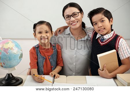 Elementary School Teacher Hugging Her Smiling Pupils