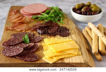 Appetizer Table For Wine Or Beer With Sausages, Dried Meat And Cheese, Served With Grissini, Herbs A