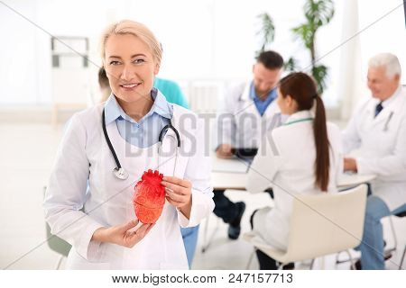 Female Doctor Holding Heart Model In Clinic. Cardiology Center