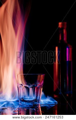 Close Up View Of Flame, Empty Glass And Bottle Of Sambuca Alcohol Drink On Black Background