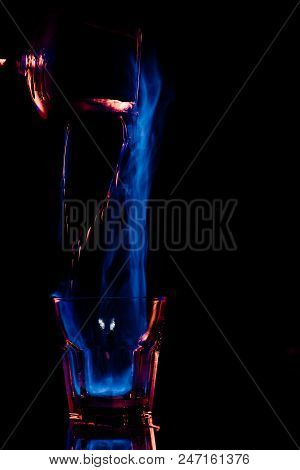 Close Up View Of Pouring Burning Sambuca Alcohol Drink Into Glass Process On Black Background