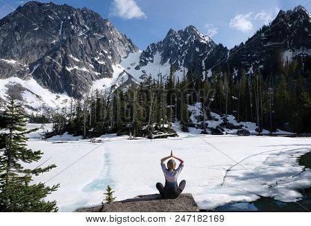 Inner Peace And Mindfulness. Woman Meditating On Scenic Lake Shore With Beautiful View Of Snow Cover
