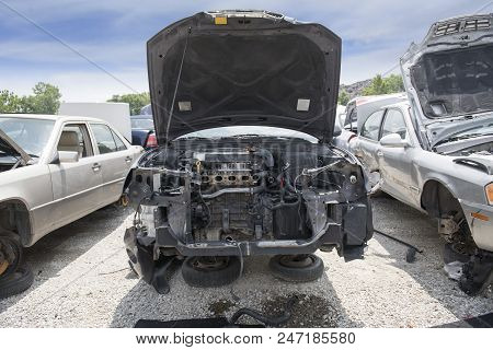 The Engine Compartment Of A Wrecked Car Reveals Missing Parts, Inlcuding The Bumper, The Radiator An