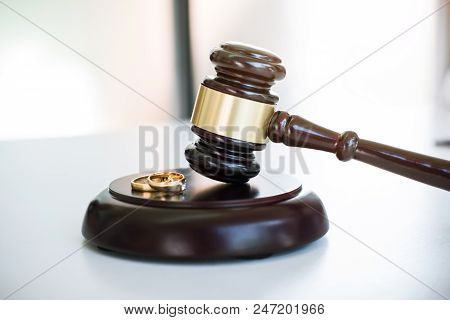 Close Up Of Judge Gavel Deciding On Marriage Divorce And Two Golden Marriage Ring.