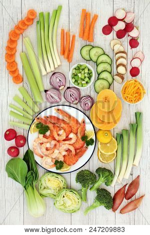 Macrobiotic health food concept with prawns and crevette seafood selection and fresh vegetables with foods high in protein, antioxidants, vitamins and minerals. On rustic white wood , top view.