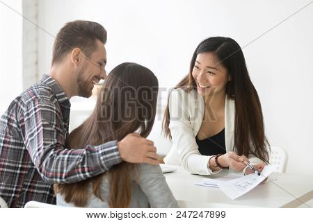 Smiling Female Real Estate Asian Talking About House Plan To Excited Millennial Couple, Ready To Buy